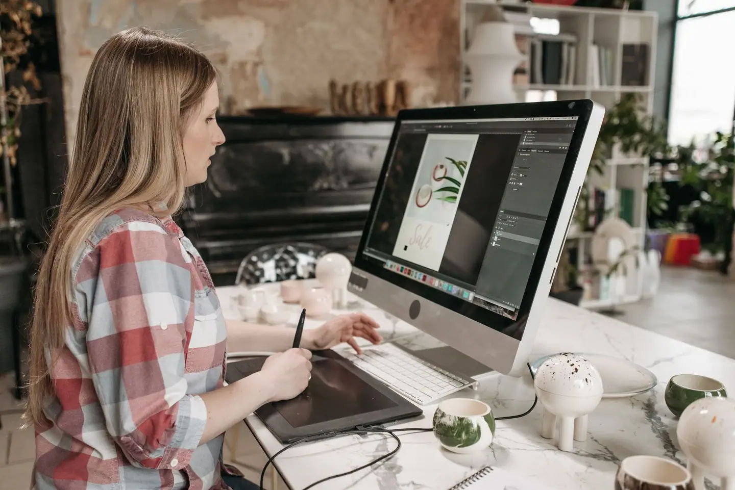 Designerin arbeitet mit Zeichentablett an einem Layout am großen Bildschirm