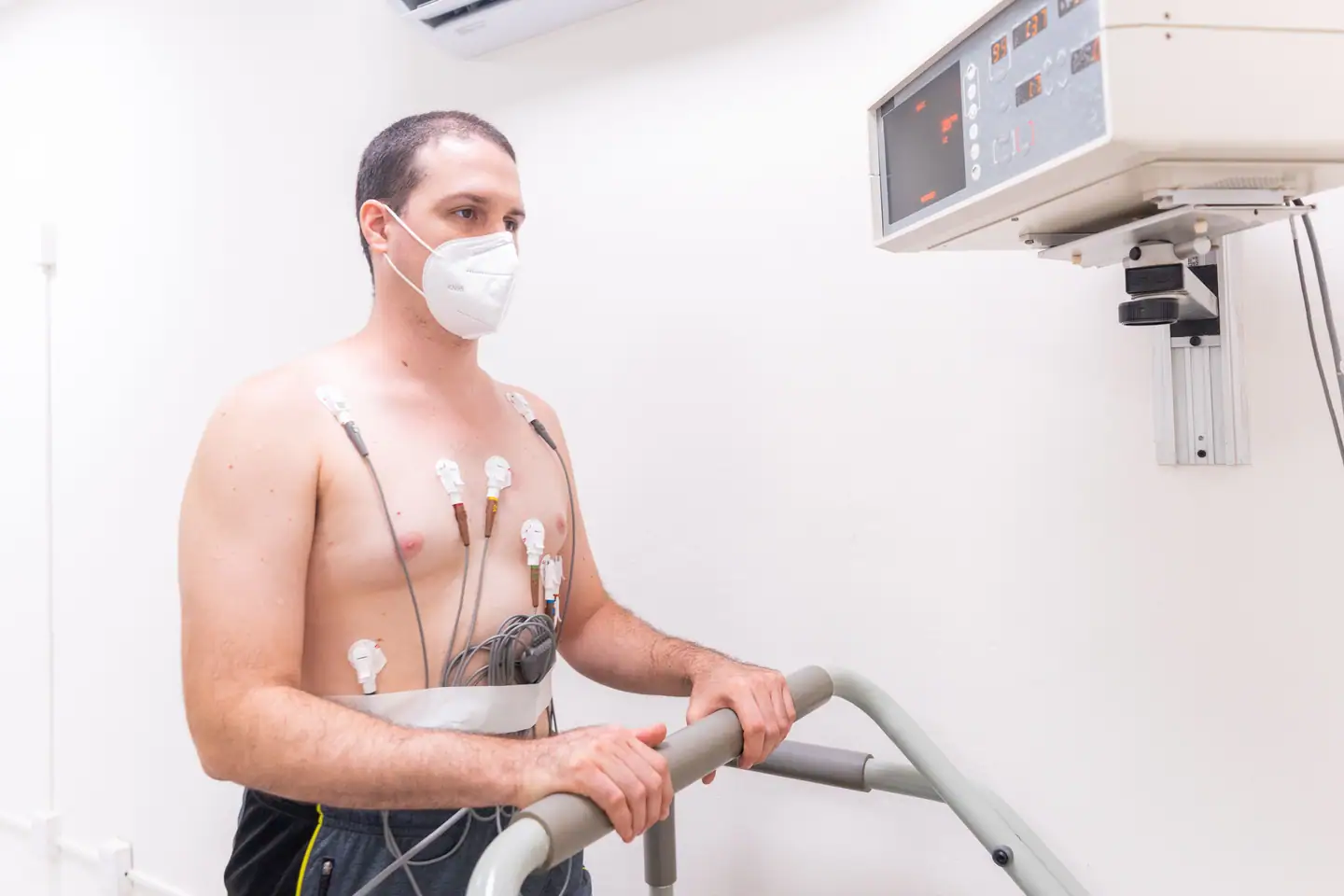 Belastungs-EKG: Patient mit Elektroden auf dem Laufband, darüber der Monitor