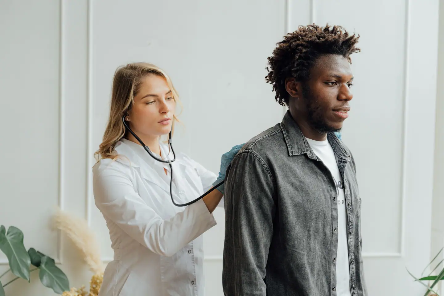 Ärztin hört einem Patienten mit dem Stethoskop den Rücken ab
