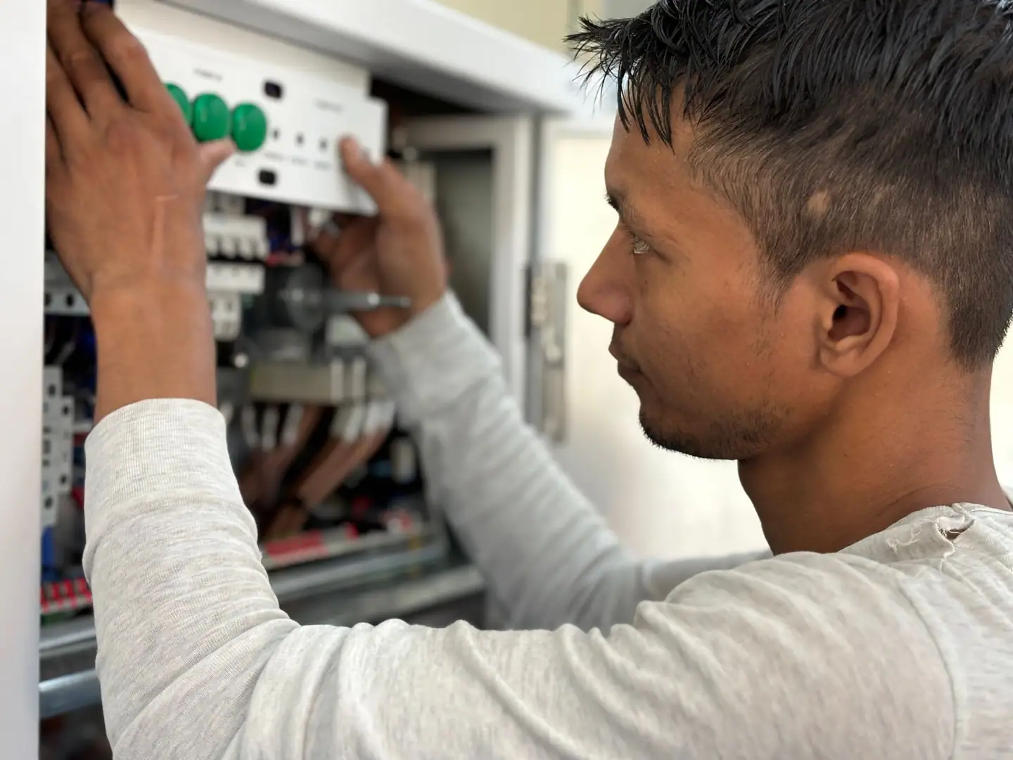 Elektriker setzt ein Bauteil in einen offenen Schaltschrank ein