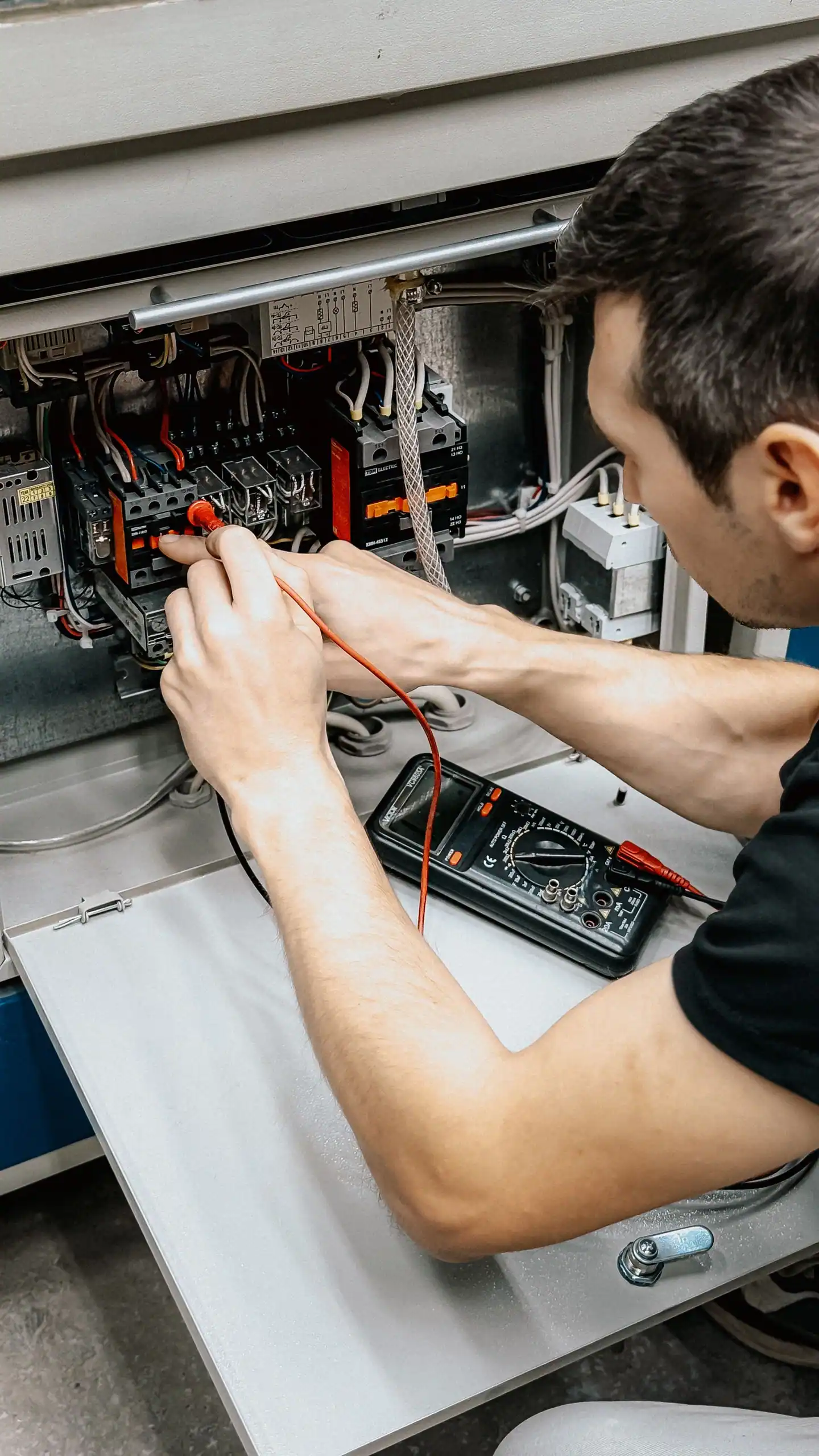 Elektriker misst mit dem Multimeter an einem offenen Schaltkasten