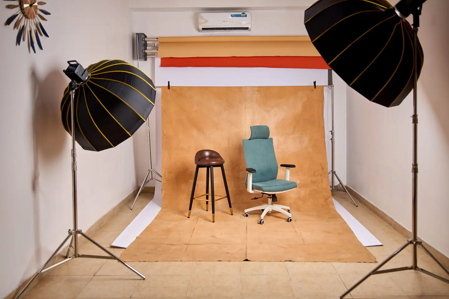 Kleines Atelier mit braunem Hintergrundkarton, zwei Parabolschirmen, Hocker und Stuhl