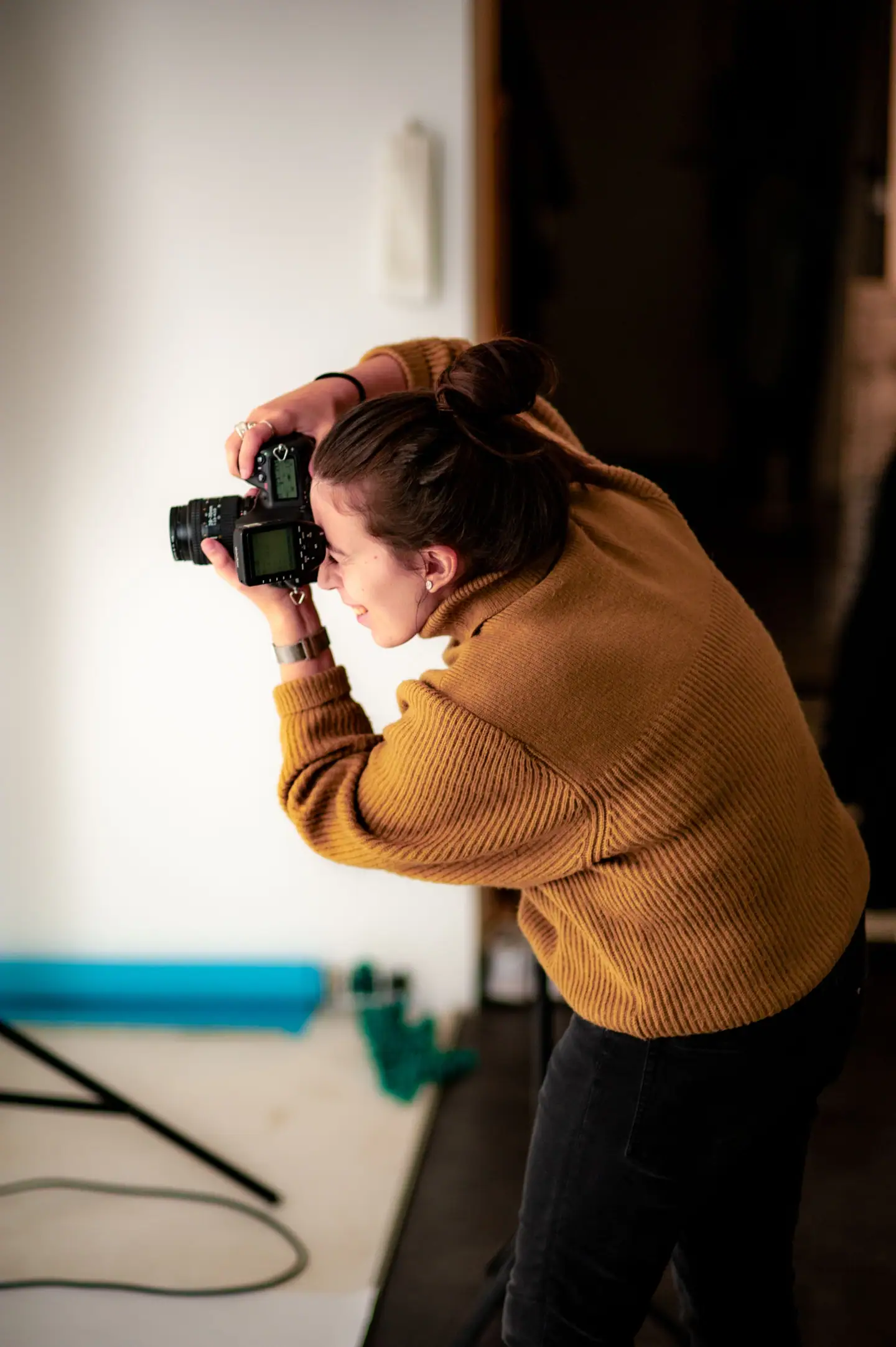 Fotografin beugt sich mit der Kamera über ein Motiv, im Hintergrund Papierrollen