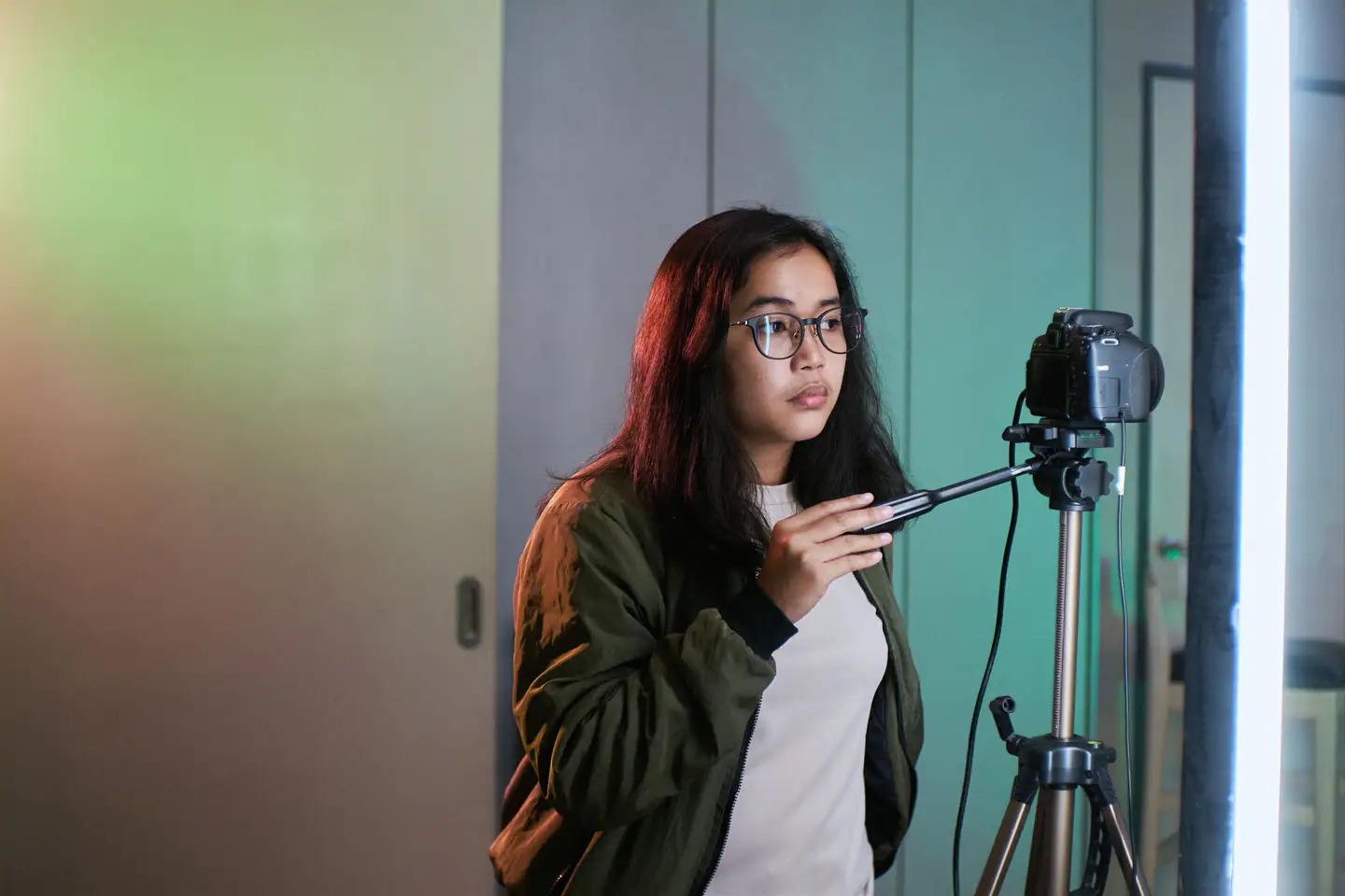 Fotografin richtet die Kamera auf dem Stativ ein, daneben das Studiolicht