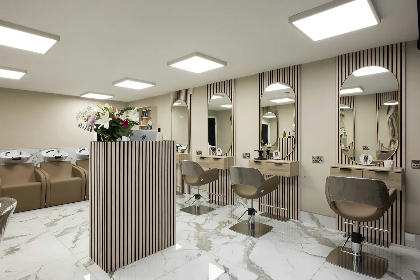 Heller Salon mit ovalen Spiegeln, Holzlamellen, Tresen und Waschplätzen