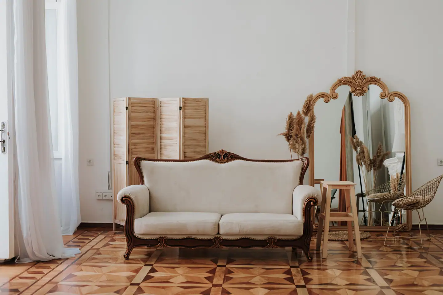 Wohnzimmer mit Tafelparkett, Stilsofa, Paravent und goldgerahmtem Spiegel