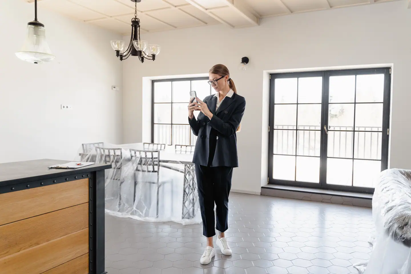 Maklerin fotografiert eine leere Wohnung mit großen Fenstern für das Exposé