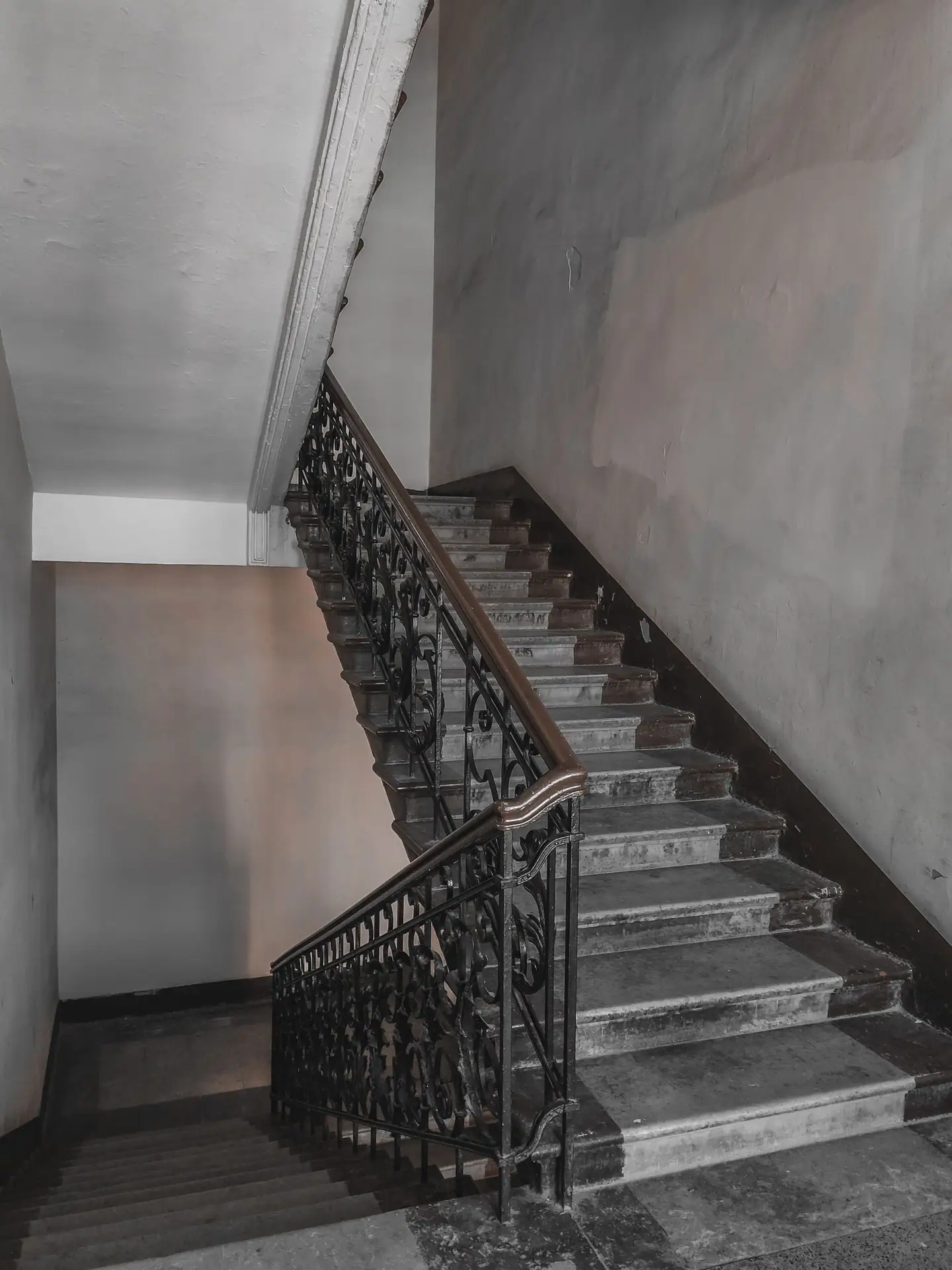 Altes Stiegenhaus mit Steinstufen und verziertem Schmiedeeisengeländer