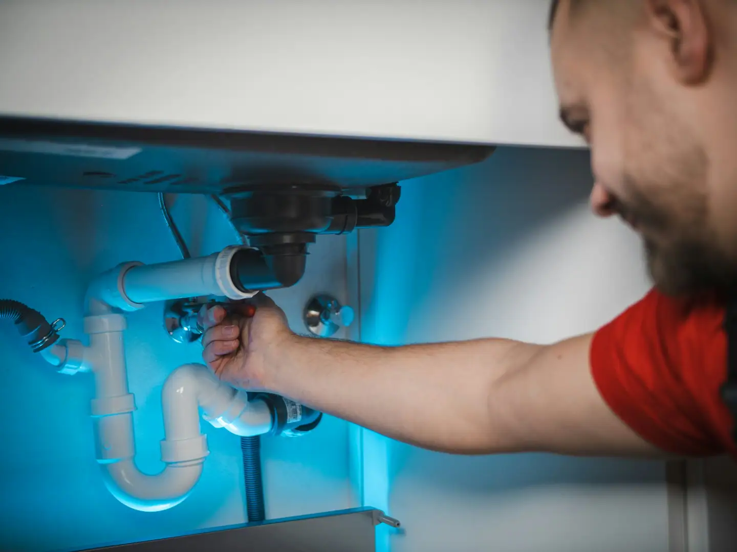 Hand zieht die Verschraubung am Siphon unter dem Waschtisch nach