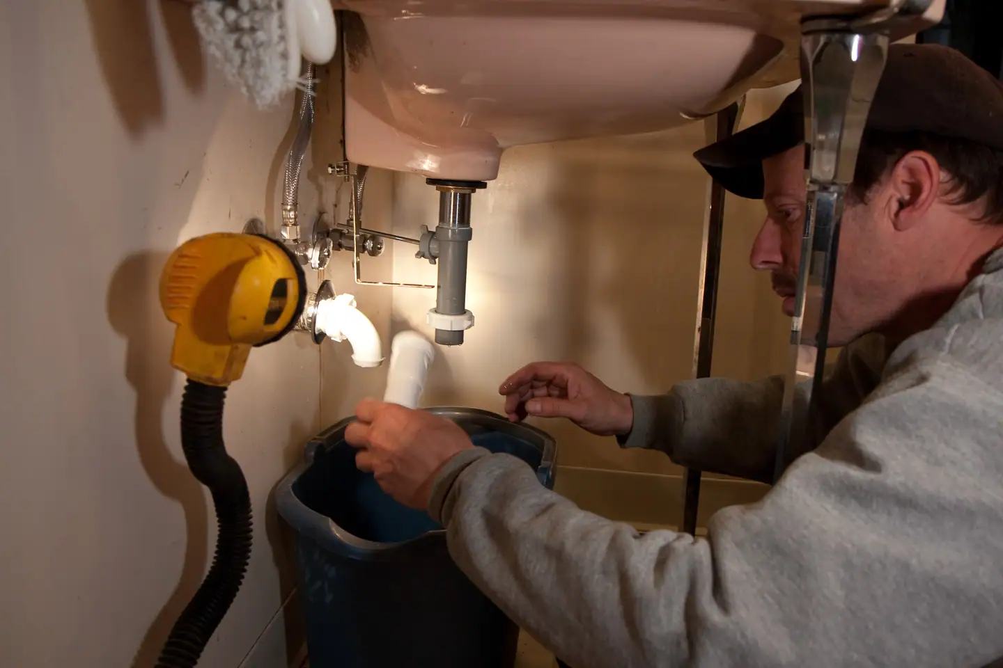 Monteur arbeitet mit Stirnlampe am Abfluss unter einem Waschbecken