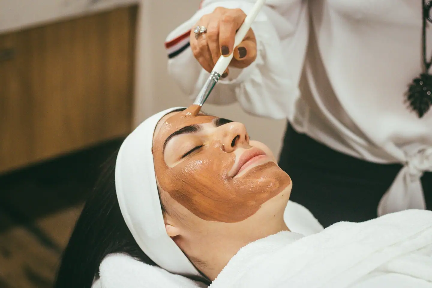 Tonerde-Maske wird mit dem Pinsel auf das Gesicht aufgetragen