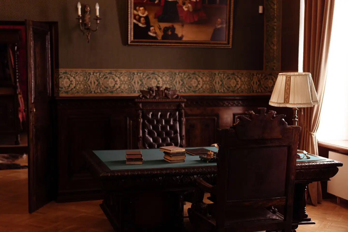 Klassisches Arbeitszimmer mit dunklem Holzschreibtisch, Tischlampe und Ölgemälde