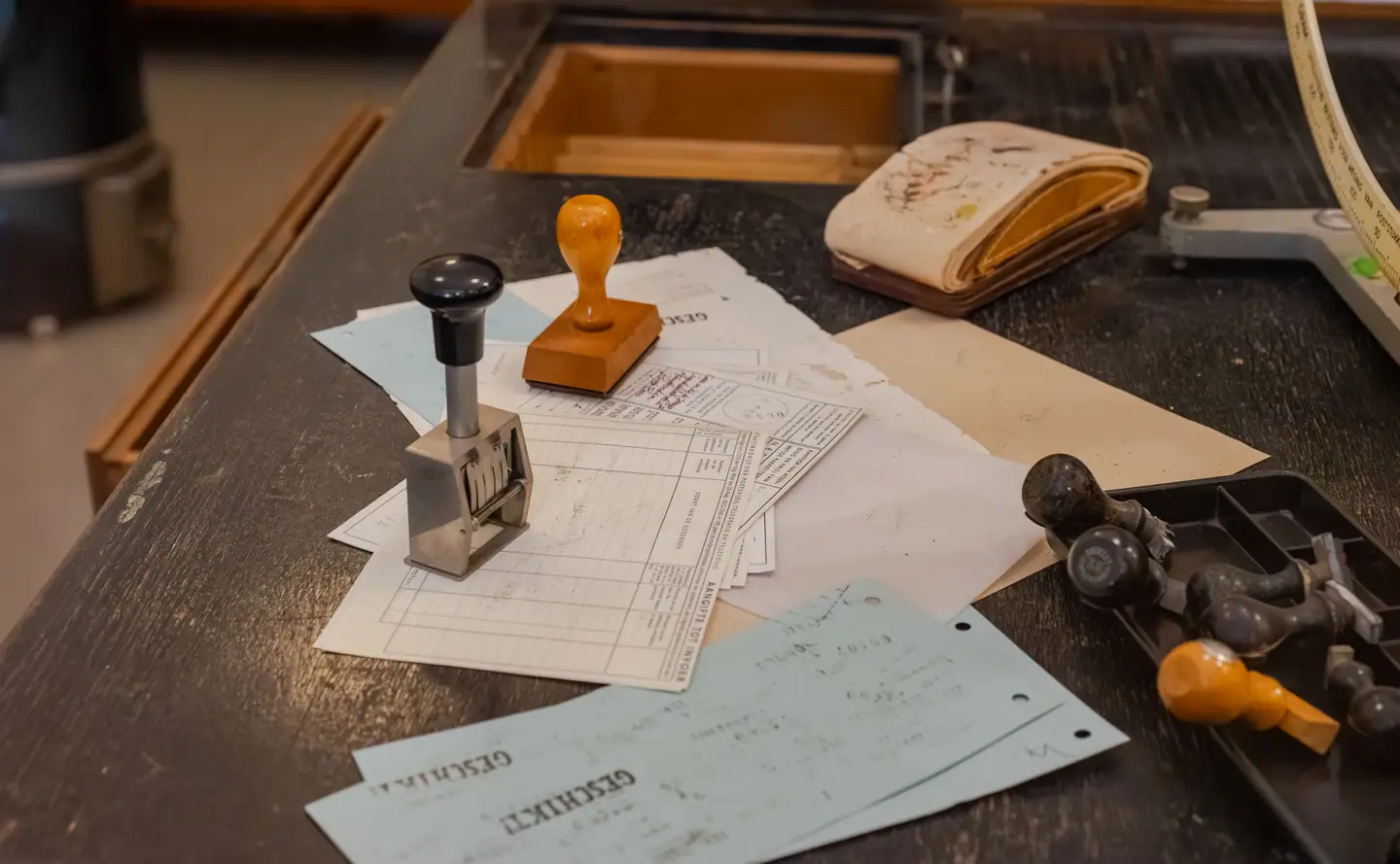 Abgegriffener Schreibtisch mit Datumsstempel, Holzstempeln und abgestempelten Durchschlägen
