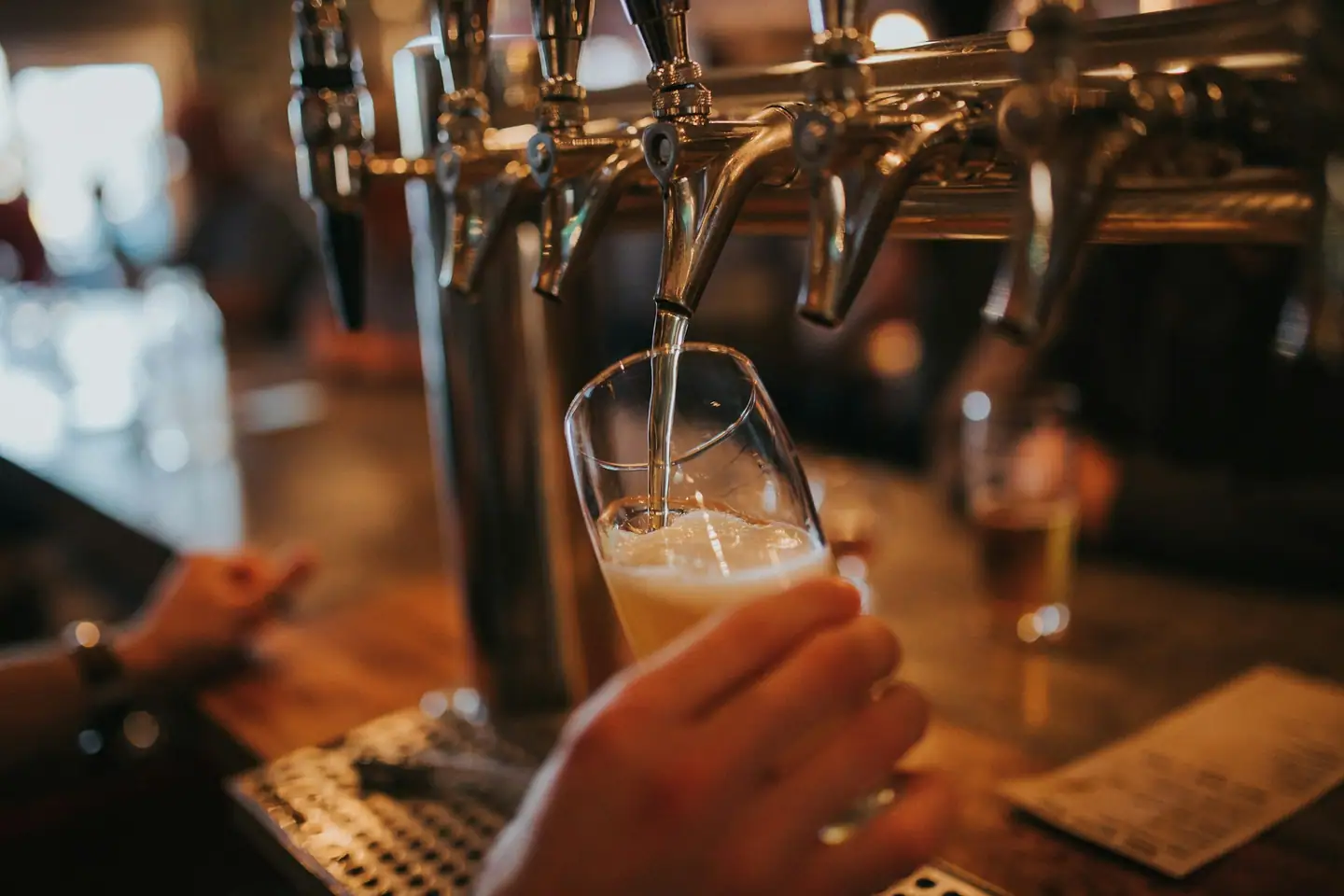 Bier wird an der Schank frisch aus dem Zapfhahn ins Glas gezapft
